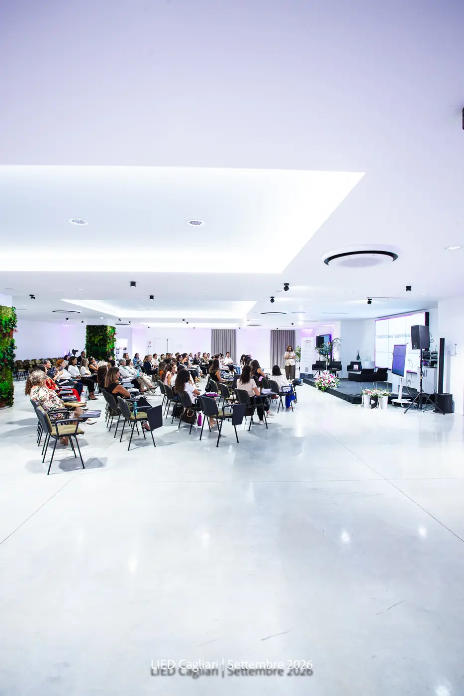 Cagliari — L'Impresa è Donna 2026 La sala di Cagliari illuminata di magenta con la platea al completo