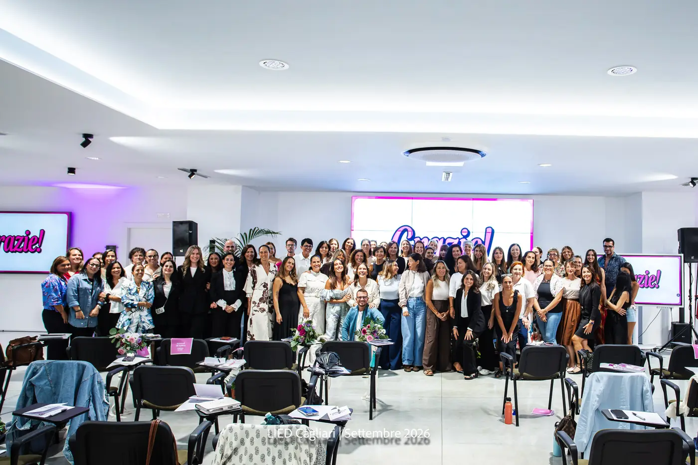 Cagliari — L'Impresa è Donna 2026 La platea di Cagliari riunita per la foto di gruppo nella sala illuminata di magenta