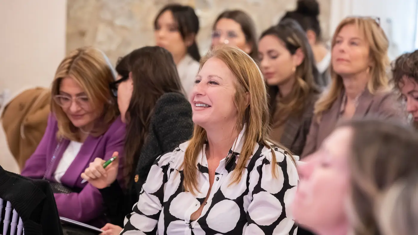 Desenzano del Garda — L'Impresa è Donna 2026 Una partecipante ascolta divertita un intervento dal palco