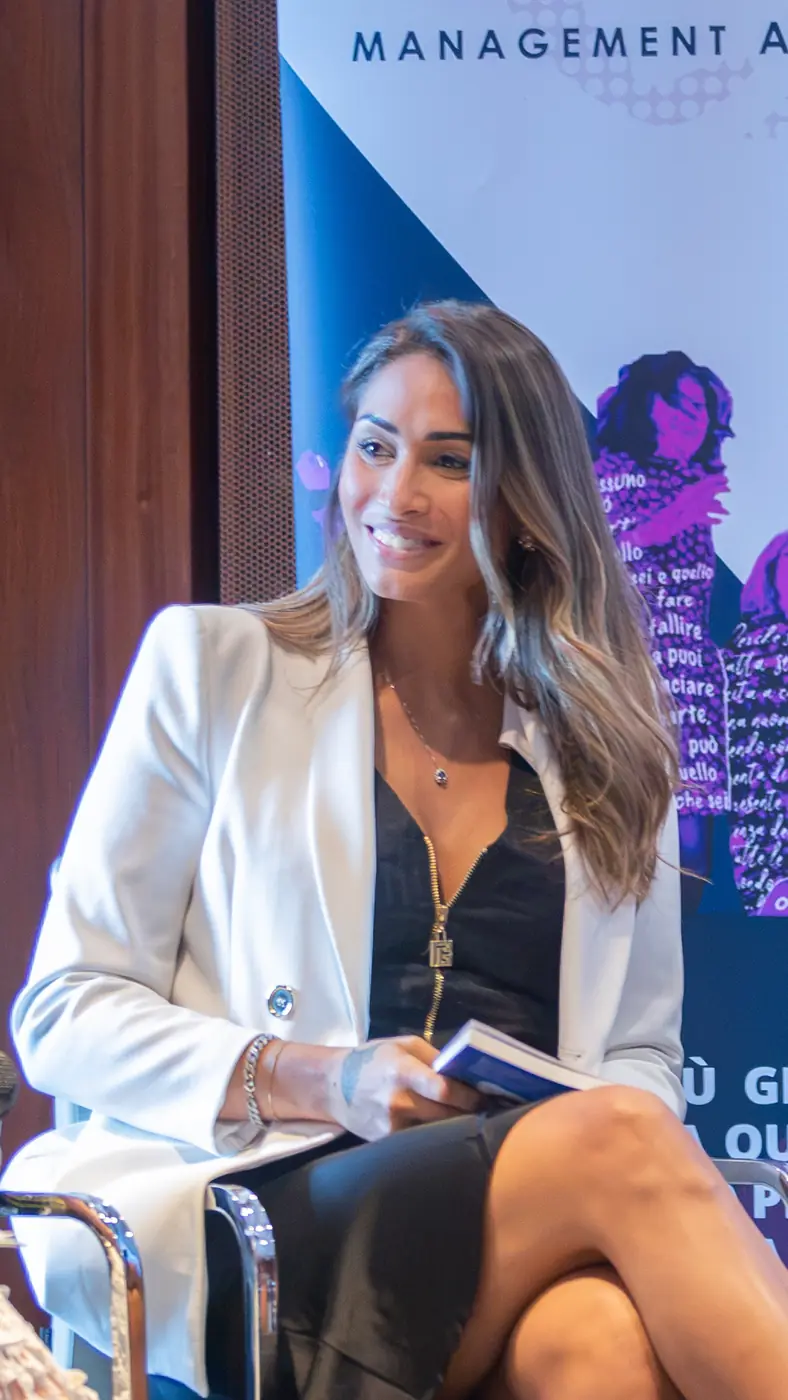 Genova — L'Impresa è Donna 2026 Una relatrice in blazer bianco seduta accanto al totem de L'Impresa è Donna