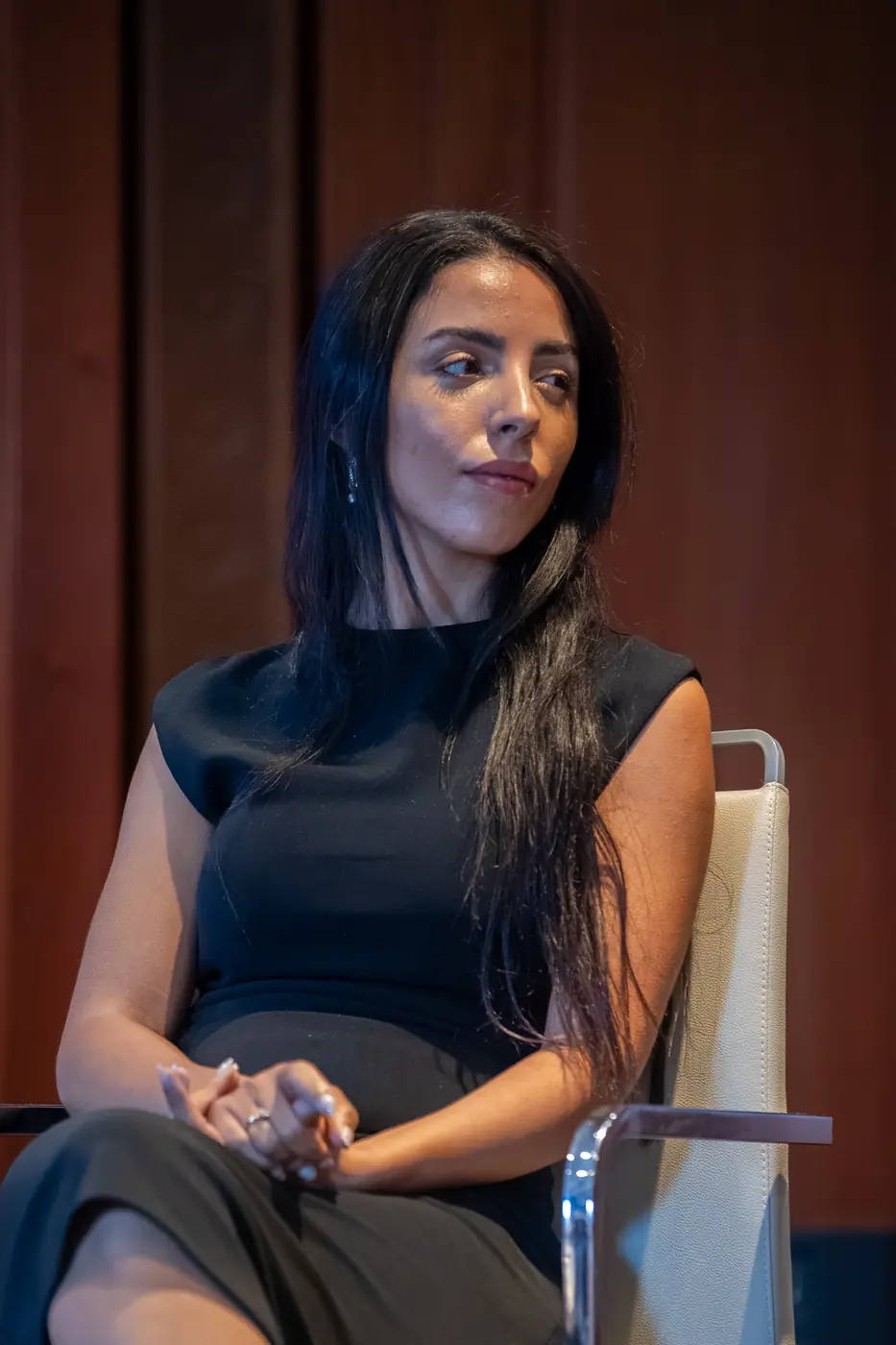 Genova — L'Impresa è Donna 2026 Una relatrice in abito nero ascolta gli altri interventi sul palco di Genova