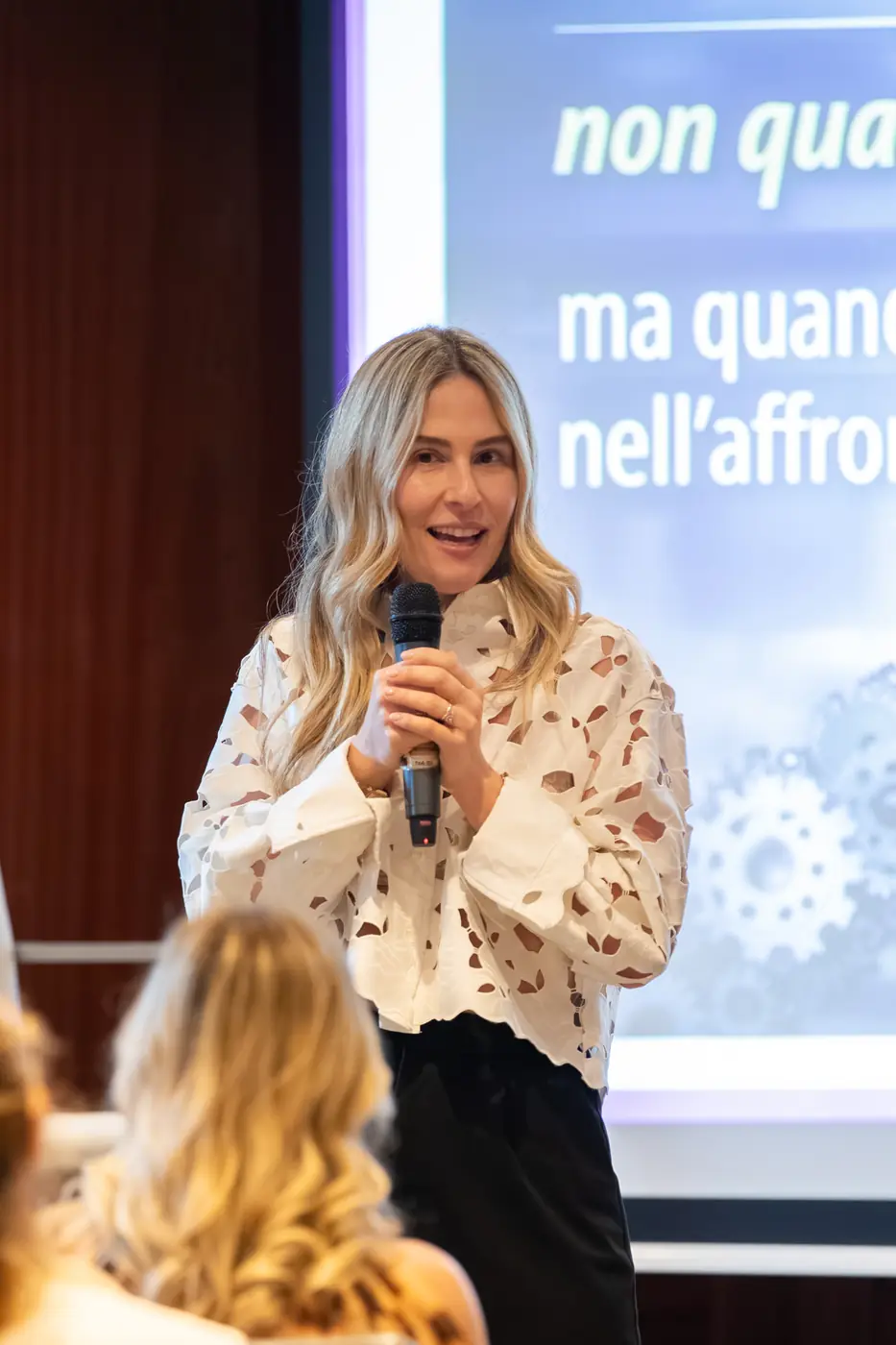 Genova — L'Impresa è Donna 2026 Una relatrice bionda parla al microfono davanti alla slide del suo intervento