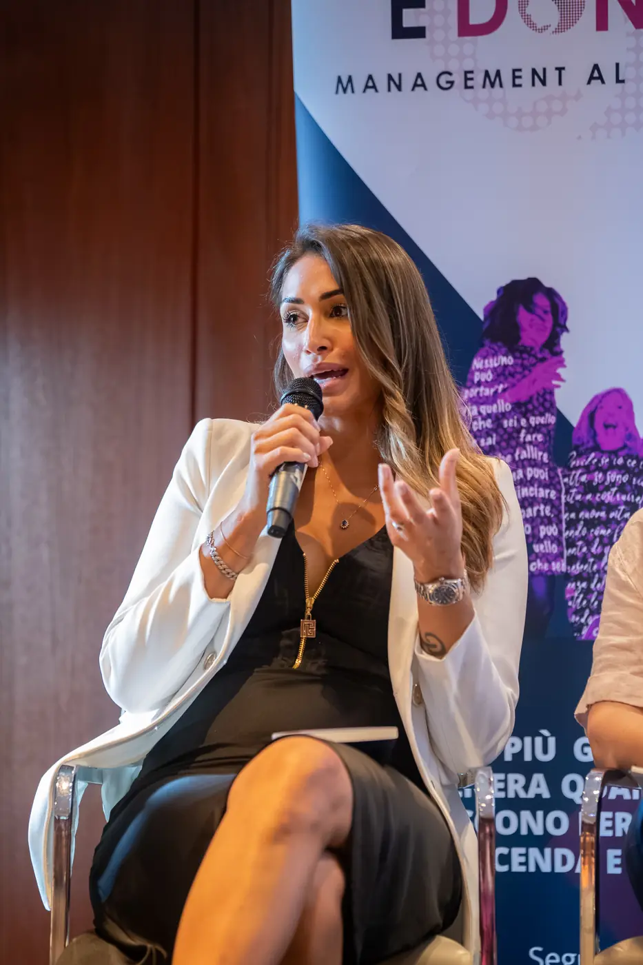 Genova — L'Impresa è Donna 2026 Una relatrice in blazer bianco parla al microfono accanto al totem del tour