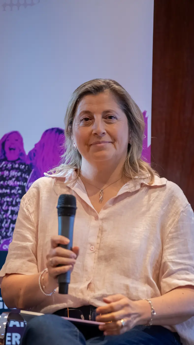 Genova — L'Impresa è Donna 2026 Una relatrice in camicia rosa interviene al microfono seduta sul palco